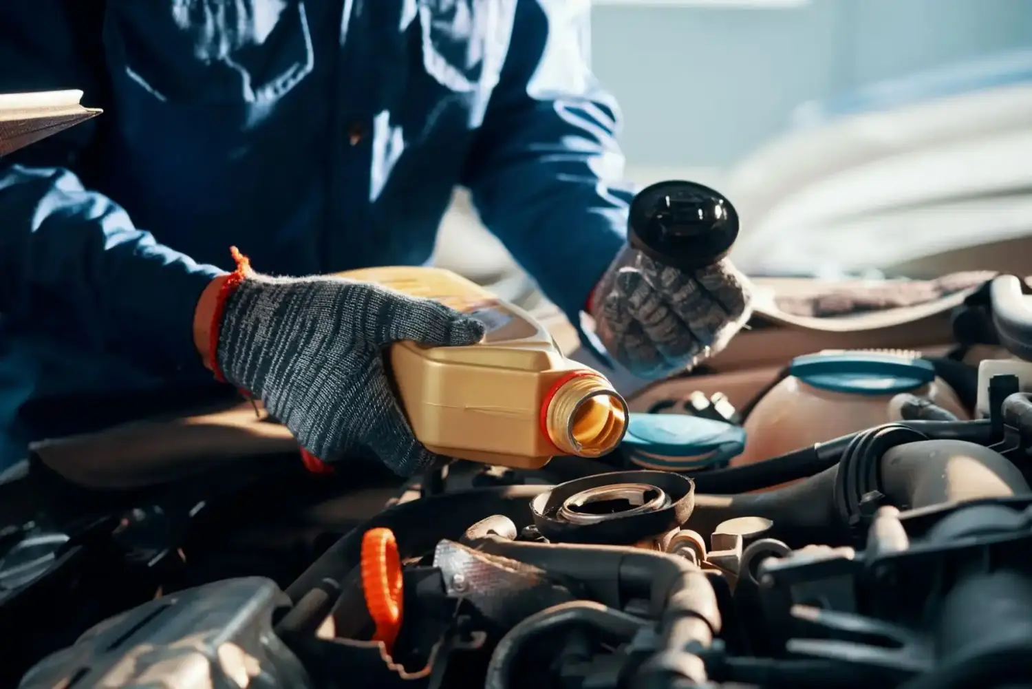 Hände eines Mechanikers gießen eine Flasche Öl in den Automotor