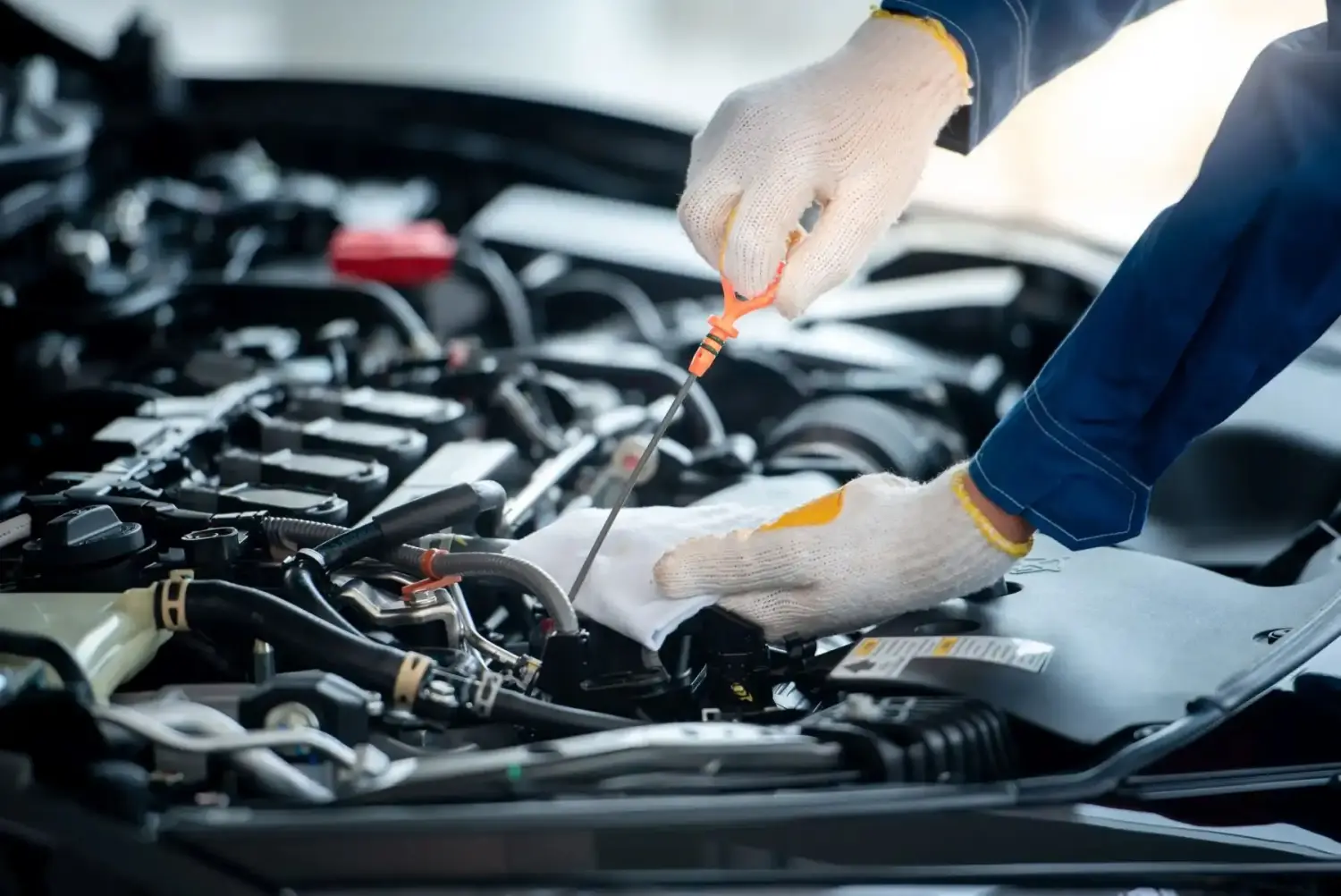 Asiatischer Automechaniker in einer Autowerkstatt prüft den Motor.